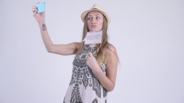Portrait of happy blonde tourist woman taking selfie with paper sign - Filmati, video