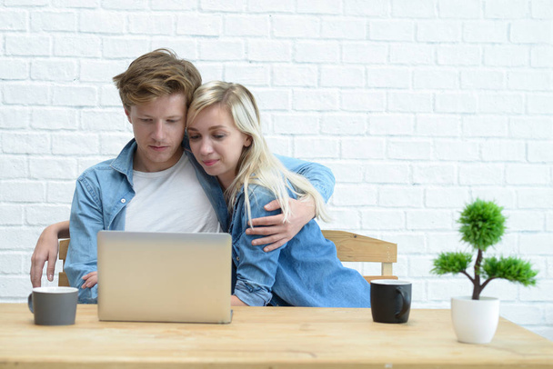 junges Paar, das sein Familienbudget verwaltet, sitzt auf dem weißen  - Foto, Bild