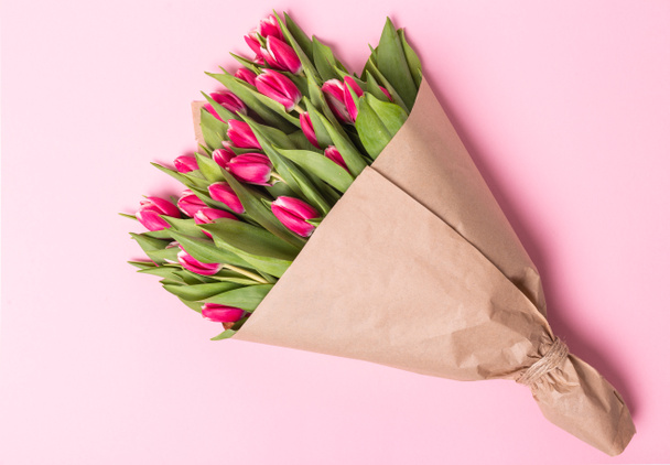 Pink tulips in kraft paper on the pink background. Flat lay, top view. - Foto, Imagem