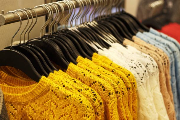 トレンディなセイロン黄色と他の色のストアにハンガーに掛かっているウールのニット セーター クローズ アップ - 写真・画像