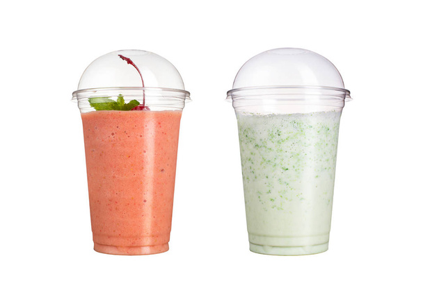 Delicious fruit smoothies in plastic cups, on a white background. Two cocktails with taste of cherry and milk. - Фото, изображение