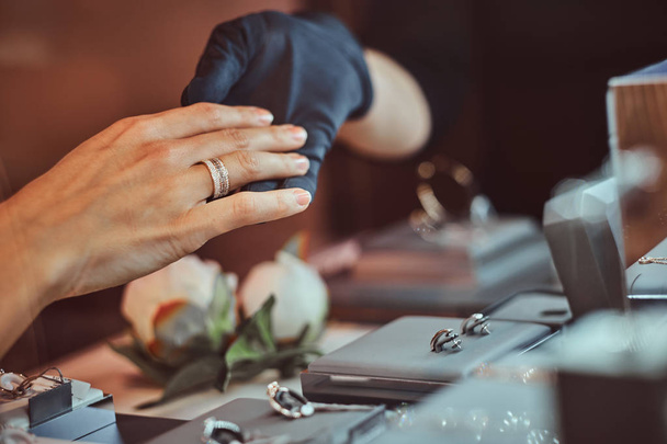 Девушка примеряет обручальное кольцо в роскошном ювелирном магазине
 - Фото, изображение