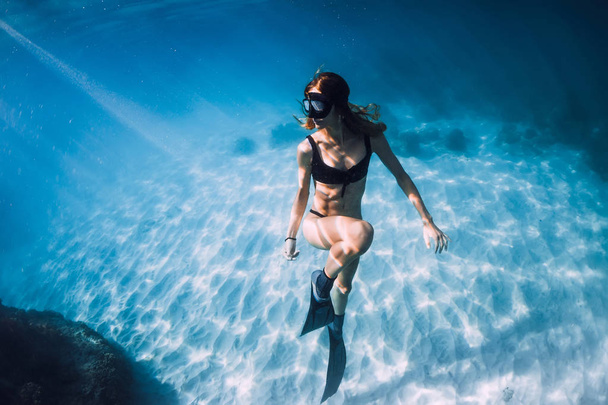 Woman freediver in bikini over sandy sea with fins. Freediving underwater in blue ocean - Photo, Image