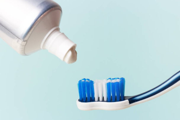 Toothpaste in tube and toothbrush on blue background. Dental hygiene concept. - Photo, Image