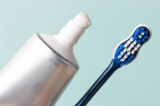 Toothpaste in tube and toothbrush on blue background. Dental hygiene concept. - Photo, Image