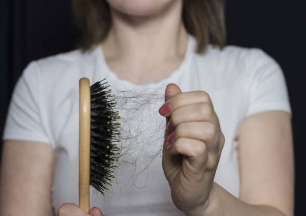 Девушка держит расческу с волосами перед собой. Проблемы с волосами... Выпадение волос
 - Фото, изображение
