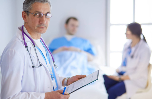 Doctor holding folder in front of a patient and a doctor - Photo, image
