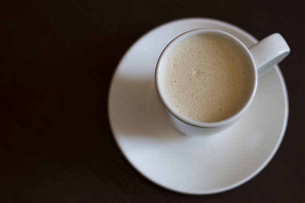 A cup of cappuccino coffee on a brown table, copy space - Foto, Imagem