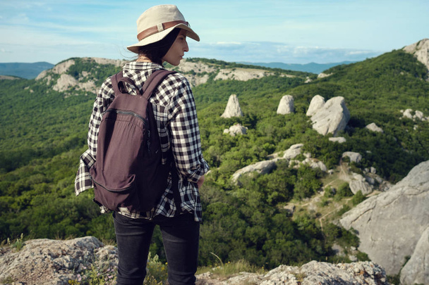 Kobieta dla podróżujących z plecakiem, trzymając kapelusz i patrząc na niesamowite gór i lasów, wanderlust travel concept, przestrzeń dla tekstu, atmosferyczne niesamowitych scen - Zdjęcie, obraz