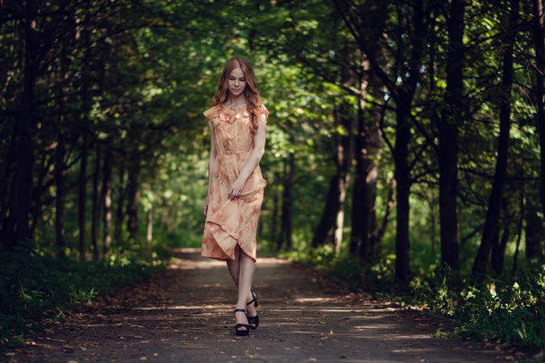 γυναίκα, φόντο καλοκαίρι πράσινο πάρκο, πράσινα φύλλα. Τρέχοντας το κορίτσι με τα όμορφα σγουρά μαλλιά - Φωτογραφία, εικόνα