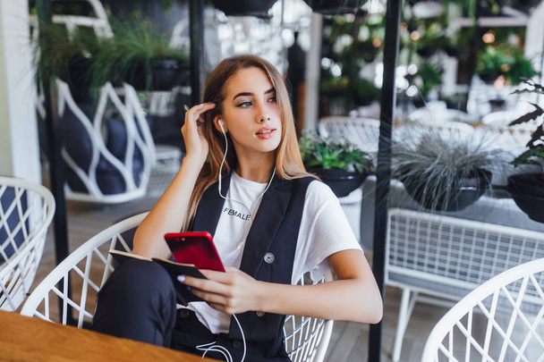 young woman listening music on earphones at cafe - Фото, изображение