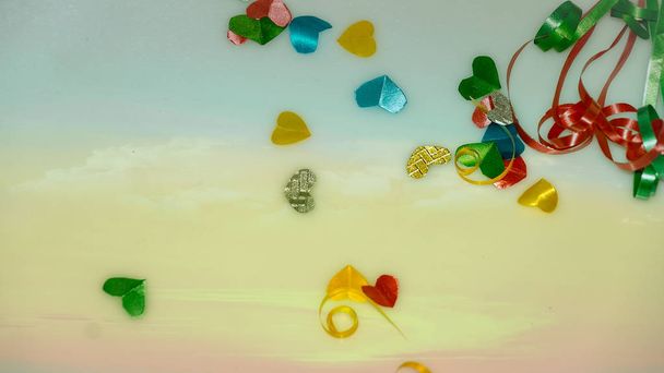 Colourful heart shape ribbon with small gift boxes on colorful bokeh, flare background. - Photo, Image