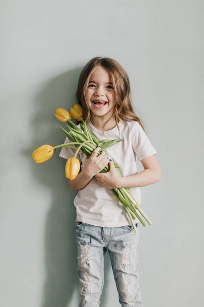 little beautiful girl with yellow tulips - Fotó, kép