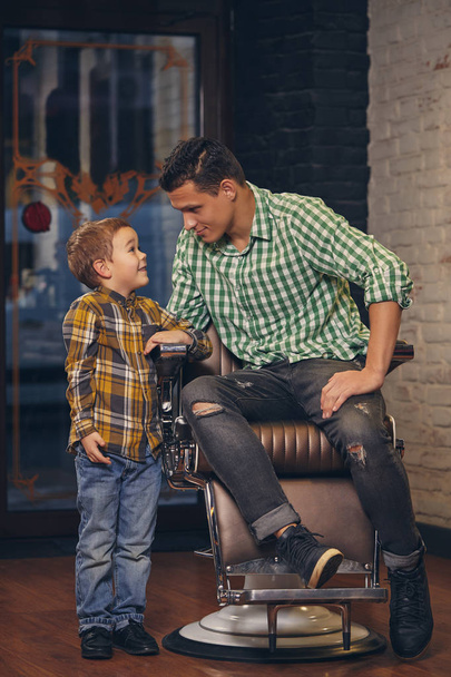 若いですハンサムな父と彼の小さなスタイリッシュな息子でbarbershop待っていますのために理髪店 - 写真・画像