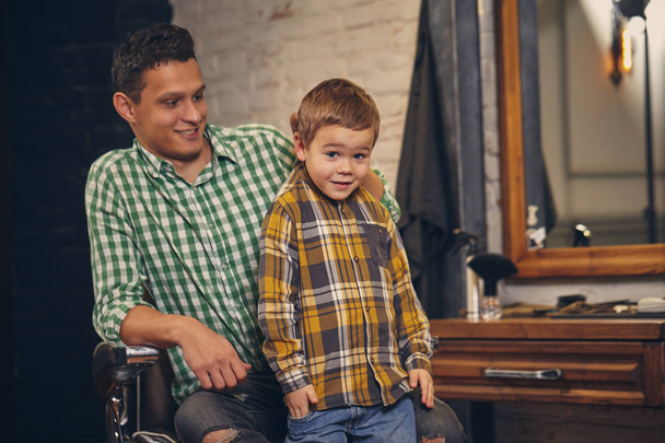 młody przystojny ojciec i jego mały stylowy syn w fryzjer czeka na fryzjera - Zdjęcie, obraz