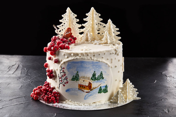 Gâteau d'hiver recouvert de glaçage blanc, avec maison peinte dans la forêt, arbres et rowan rouge
. - Photo, image