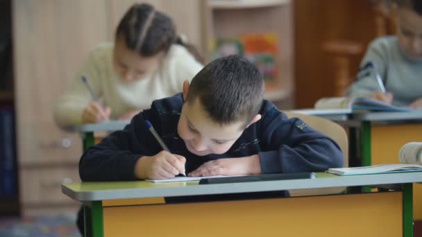 Crianças escrevem sentadas em uma mesa
 - Filmagem, Vídeo