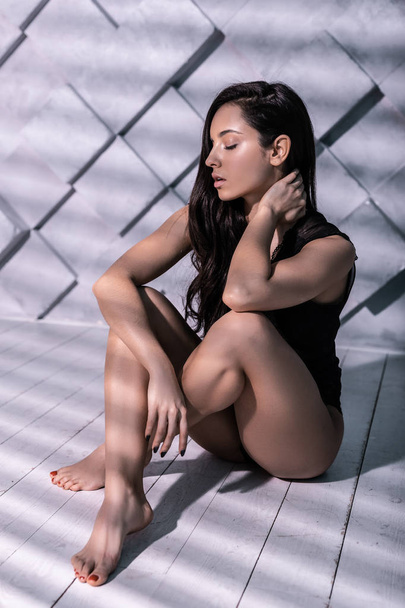 Alluring charming brunette fashion poser sitting with crossed ankles - Fotoğraf, Görsel