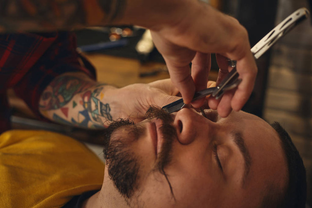 Клієнт під час гоління бородою в перукарні
 - Фото, зображення