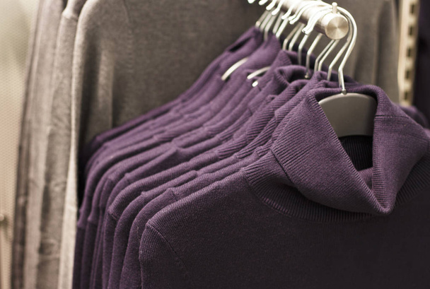 τάση Ultra ιώδες χρώμα μάλλινα πλεκτά πουλόβερ κρέμονται στις κρεμάστρες στο κατάστημα, γκρο πλαν - Φωτογραφία, εικόνα