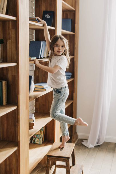 Little girl in the library  reaching for a book - Фото, зображення