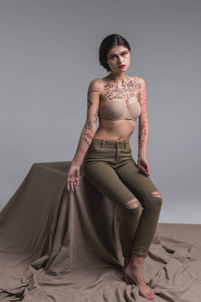 Dark-haired beautiful slim model in skinny jeans looking sad - Foto, Bild