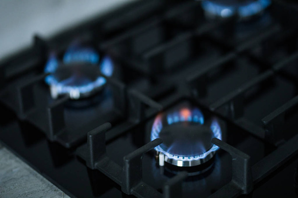 Кухонная плита с горящими газовыми кольцами. газовая плита с голубым пламенем
. - Фото, изображение