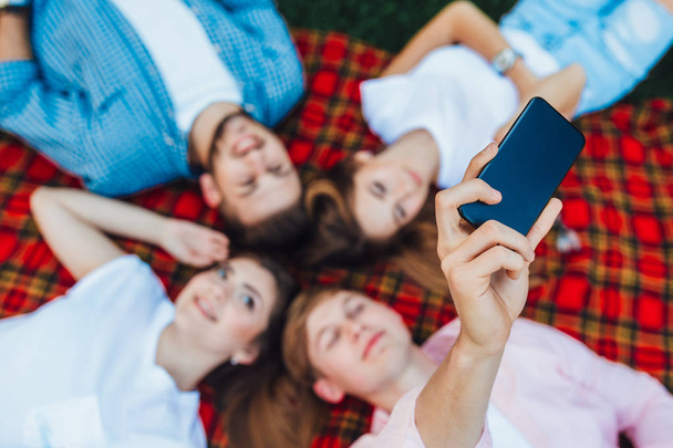 high angle view of friends lying on plaid and making selfie, selective focus - Valokuva, kuva