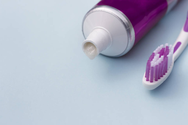 Pasta de dientes en tubo y cepillo de dientes sobre fondo azul. Concepto de higiene dental
. - Foto, imagen
