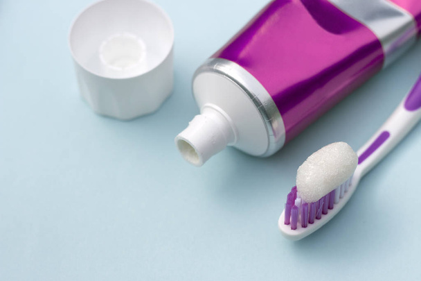 Zubní pasta v trubici a kartáček na modrém pozadí. Pojem dentální hygiena. - Fotografie, Obrázek