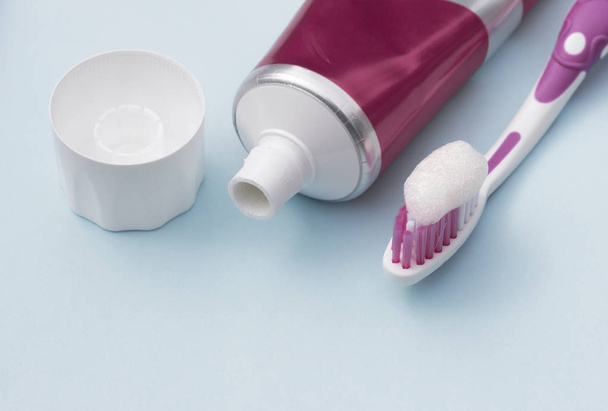 Pasta de dientes en tubo y cepillo de dientes sobre fondo azul. Concepto de higiene dental
. - Foto, imagen