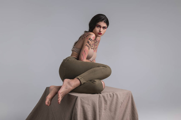 Brunette cute young model with body art in jeans looking innocent - Foto, Bild