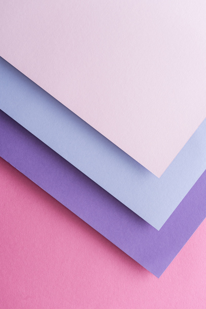 Draufsicht auf blaue, weiße und lila Papierbögen auf rosa Hintergrund mit Kopierraum  - Foto, Bild
