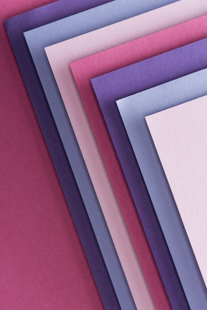 top view of blue, white, pink and purple sheets of paper on pink background  - Foto, Bild