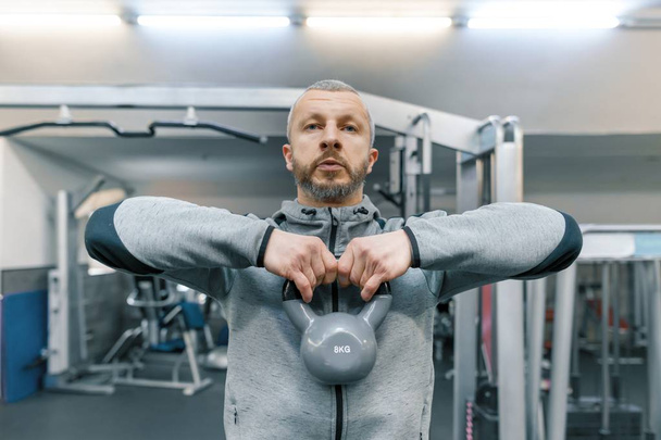 Adult age man working in training gym. Sport rehabilitation, age, healthy lifestyle concept. - Фото, изображение