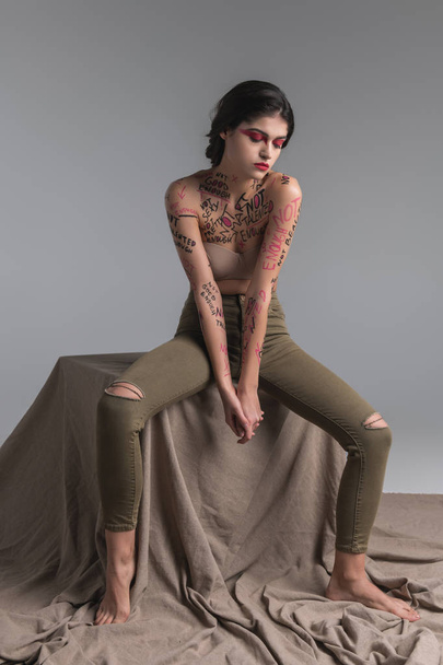 Young brunette cute slim model in skinny jeans working in the studio - Valokuva, kuva