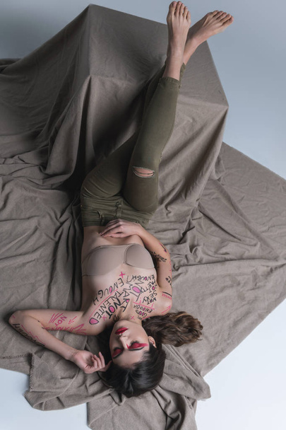 Young brunette cute slim model in skinny jeans laying on the floor - Fotoğraf, Görsel