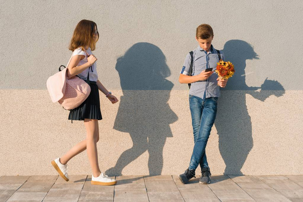 Outdoor portrait of teenagers, boy with bouquet of flowers and girl, gray wall background - Фото, зображення
