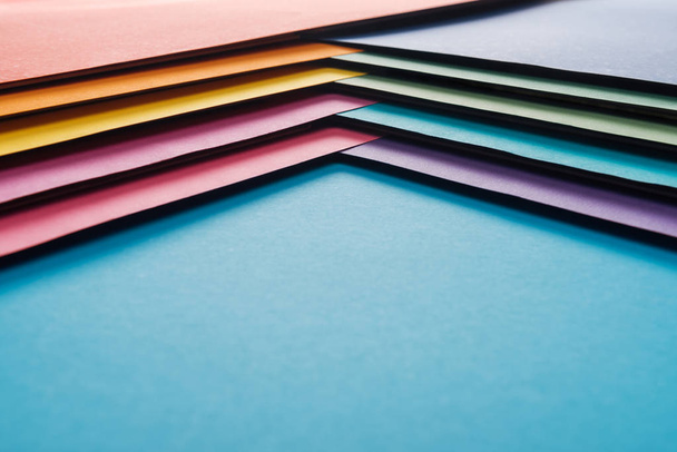 empty blue, orange, burgundy, green, yellow, pink and purple sheets of paper on blue background  - Foto, afbeelding