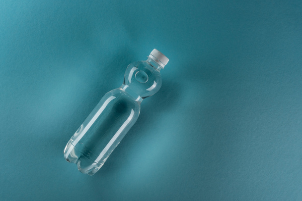 vista superior de la botella de agua de plástico sobre fondo turquesa con espacio de copia
 - Foto, Imagen