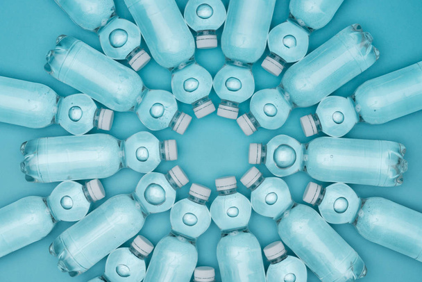 top view of transparent plastic water bottles isolated on turquoise - Fotografie, Obrázek