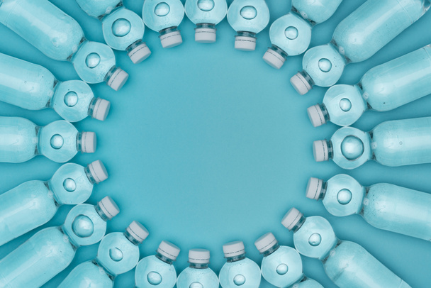 vista superior de marco redondo hecho de botellas de agua de plástico aisladas en turquesa con espacio de copia
 - Foto, Imagen