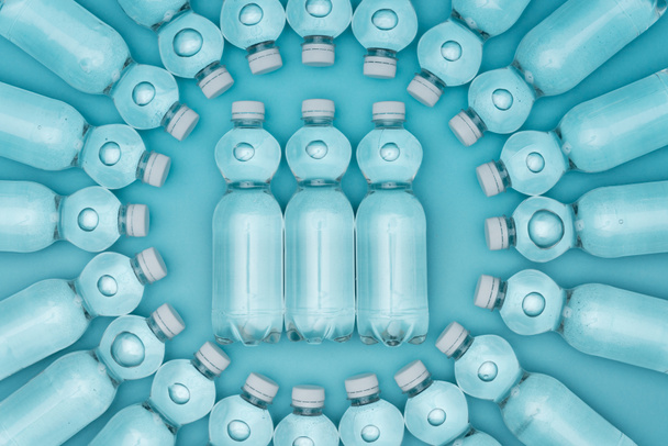top view of transparent plastic water bottles isolated on turquoise - Foto, immagini