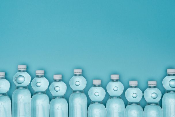 top view of plastic water bottles isolated on turquoise with copy space - Foto, afbeelding