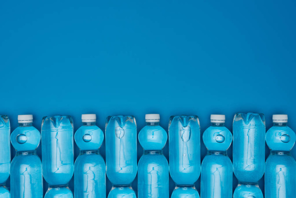 vista superior de garrafas de água de plástico dispostas isoladas em azul com espaço de cópia
 - Foto, Imagem