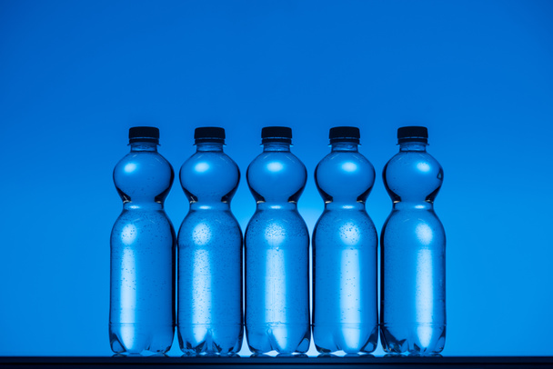 tónusú képek a neon kék háttér megvilágítású műanyag palackokkal - Fotó, kép