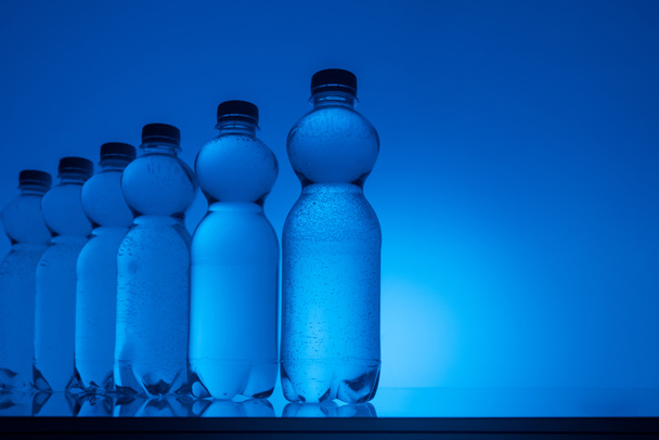 imagen tonificada de botellas de agua de plástico sobre fondo azul neón con espacio de copia
 - Foto, imagen