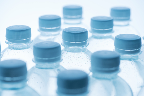 foco seletivo de garrafas de água com tampas em fundo branco
 - Foto, Imagem