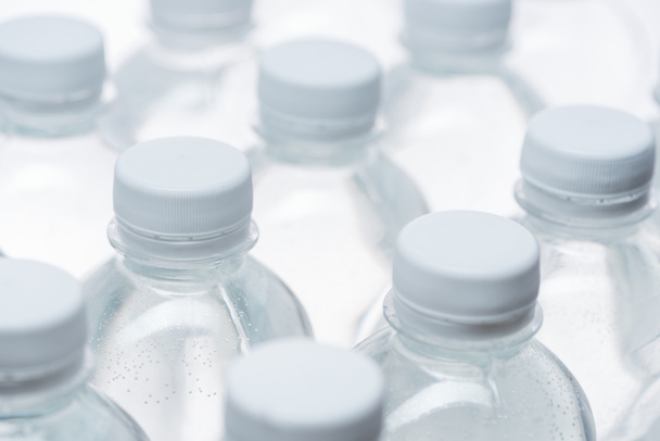 selektiver Fokus von Wasserflaschen mit Verschlüssen auf weißem Hintergrund - Foto, Bild