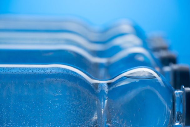 青い背景に行の泡とペットボトルの水のクローズ アップ - 写真・画像